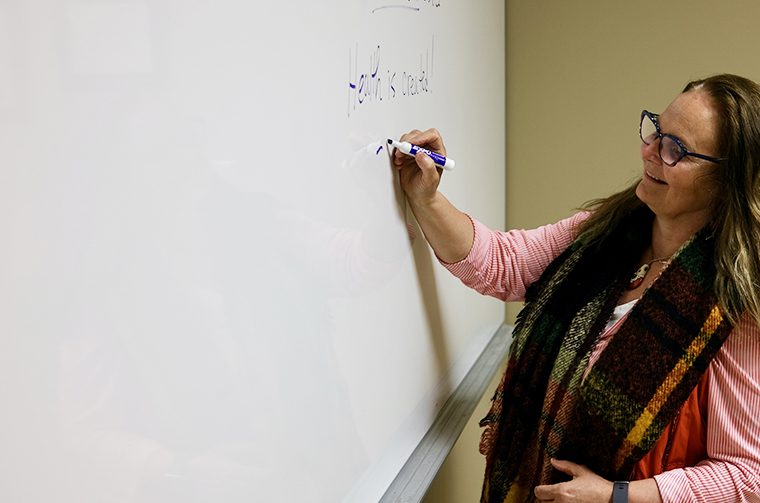 Dr. Laura MacDonald writes on a whiteboard.