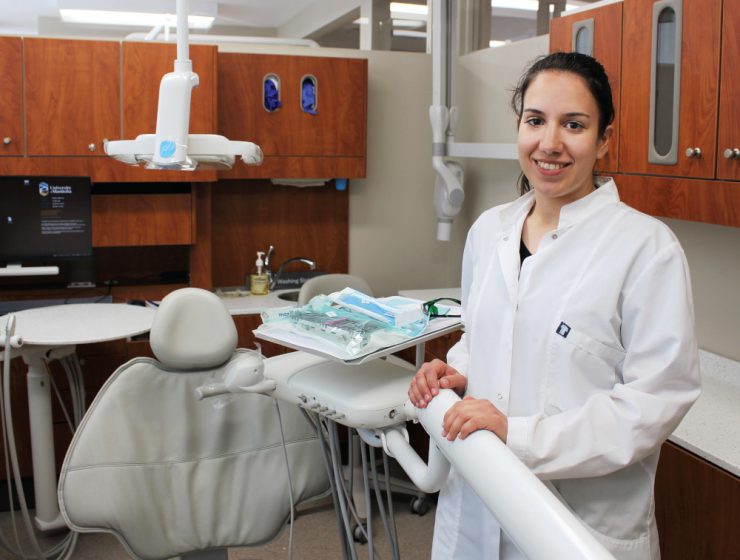 Dr. Chrysi Stavropoulou stands in a clinic next to a dental chair.