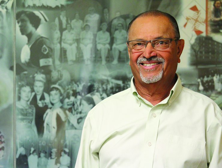 Peri Venkatesh stands in front of a historical mural at the College of Nursing's building at Fort Garry campus.